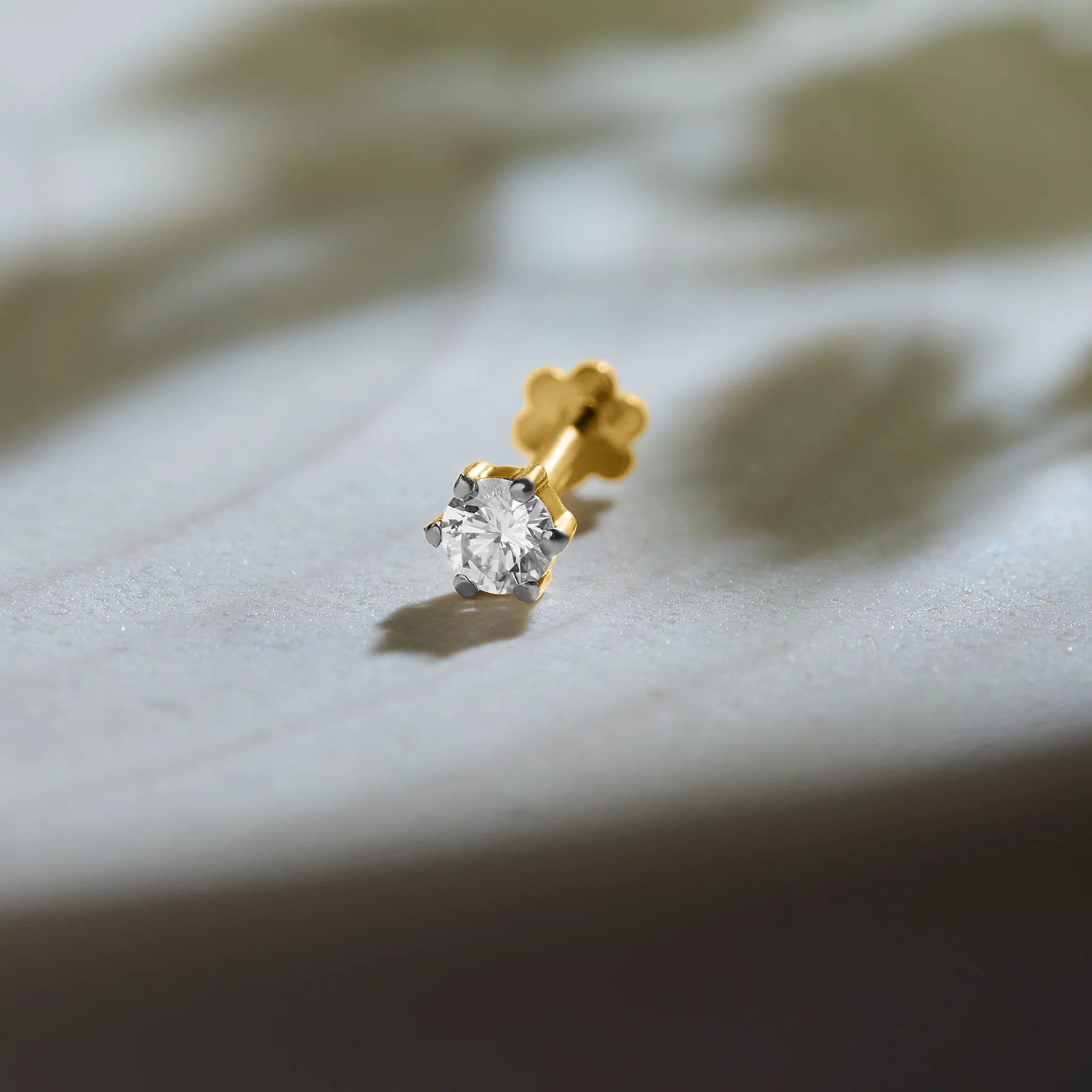 Round diamond stud earring in 14k gold, side view with soft shadow