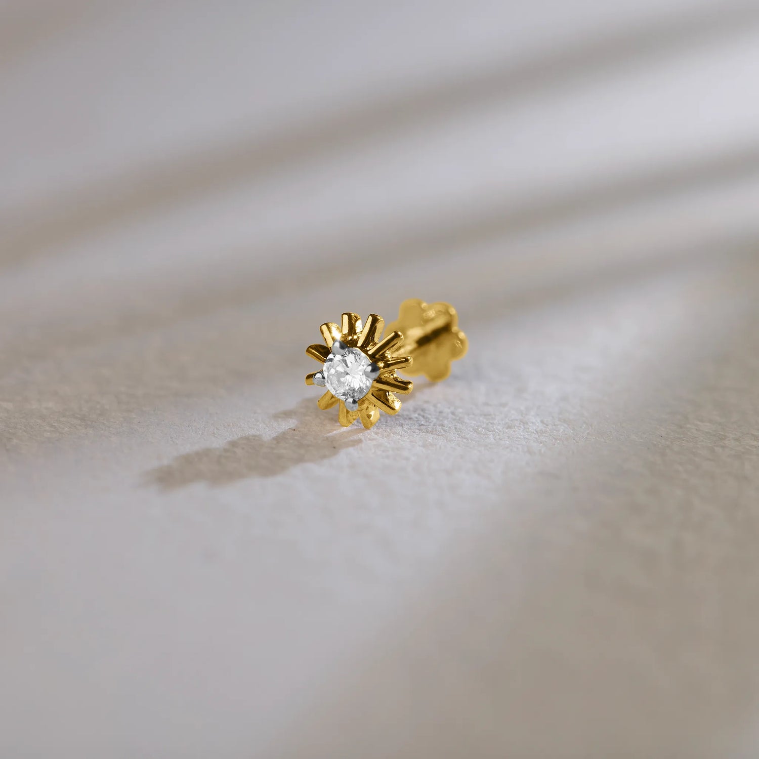 Gold sunburst diamond nose pin design on soft background