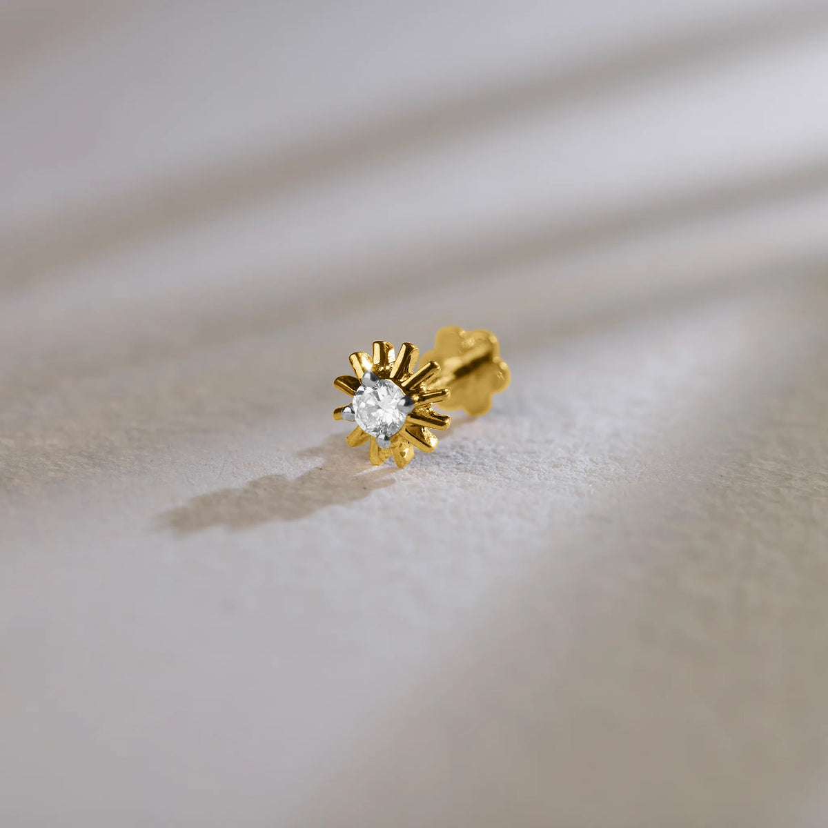 Gold sunburst diamond nose pin design on soft background