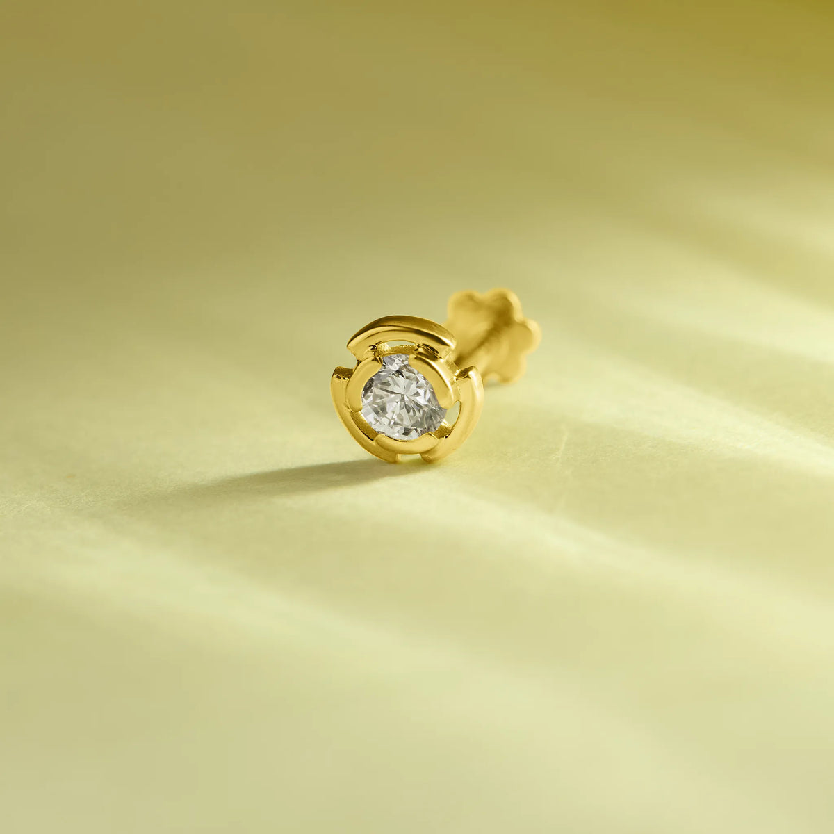 Round diamond stud earring with swirl-shaped gold bezel setting