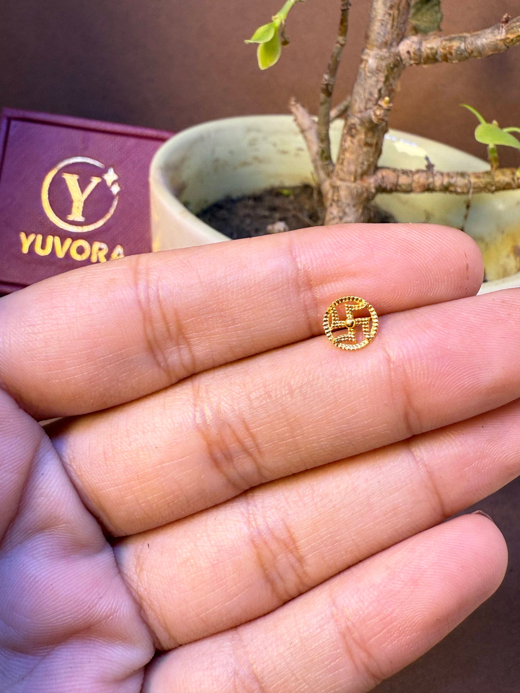 Round gold nose pin with traditional auspicious symbol in beaded border, held in hand
