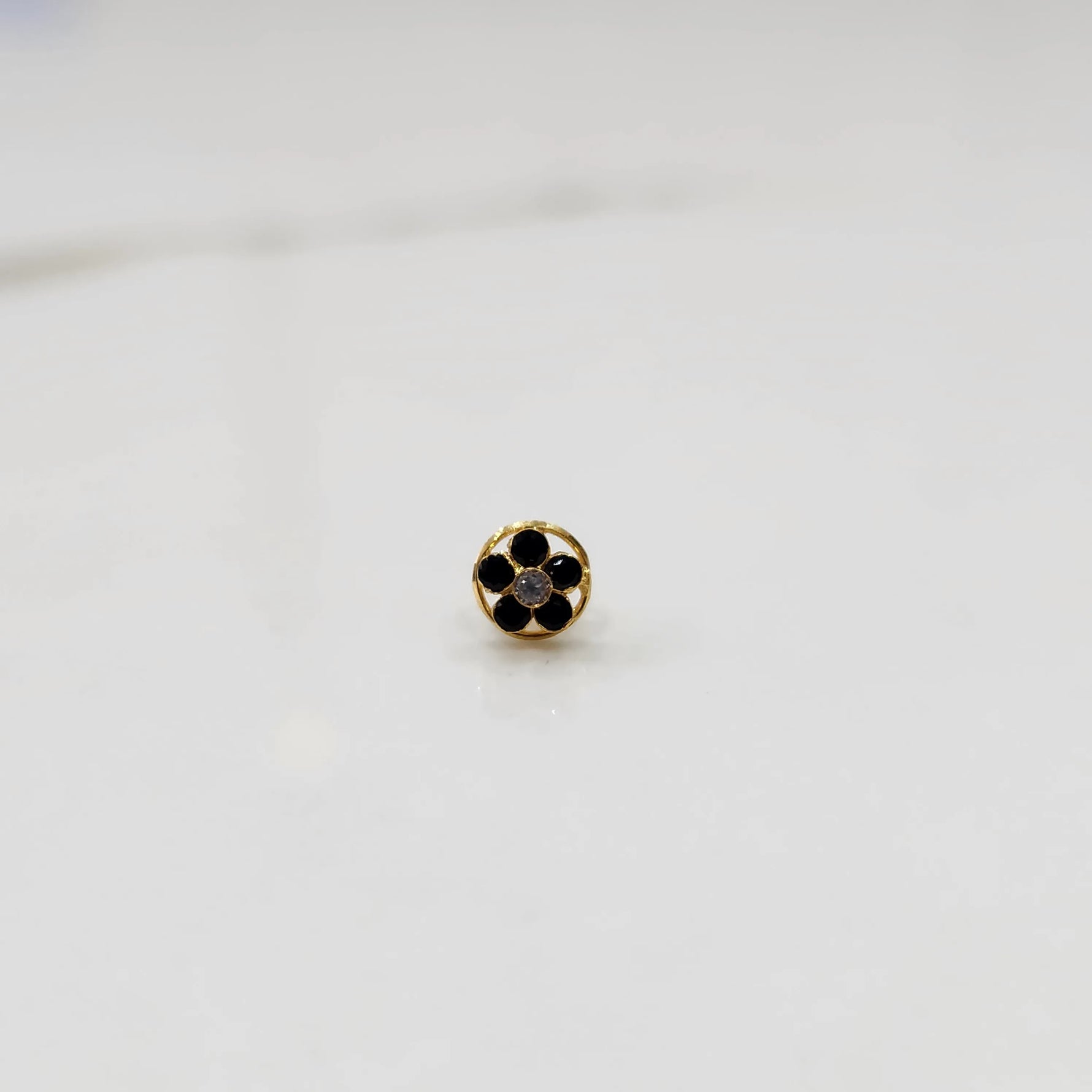 Black onyx flower cluster nose stud with round gold border, jewelry photography