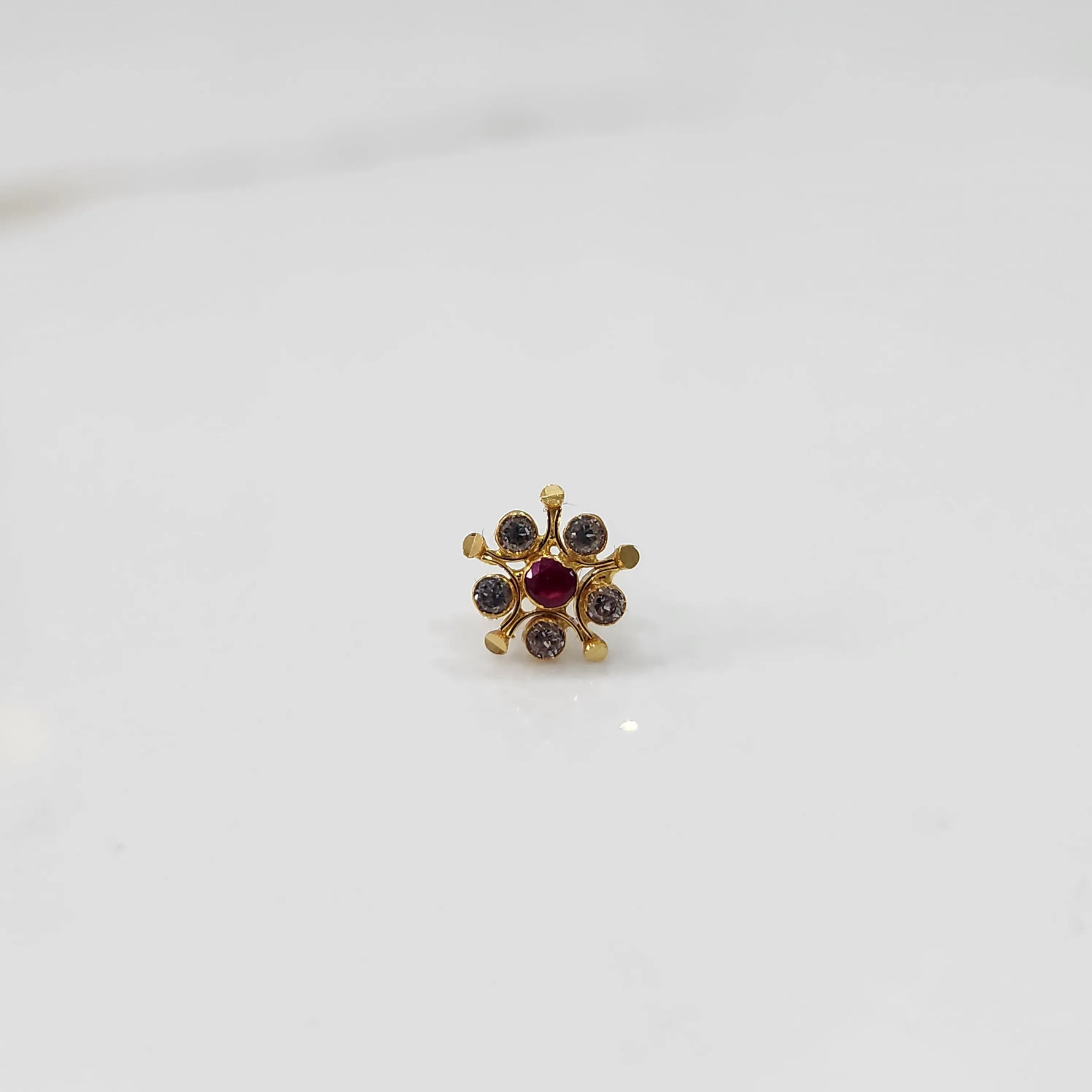 Gold nose pin with ruby center and round stone accents