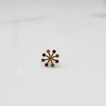 Product shot of a gold nose stud with alternating ruby and diamond stones