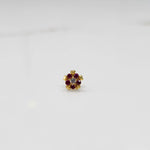Product shot of a gold nose stud with ruby flower and heart petal design