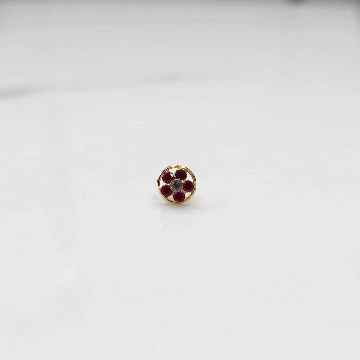 Ruby flower cluster nose stud with round gold border, jewelry photography