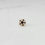 A gold nose pin shaped like a star with a deep blue center stone and clear crystal accent stones