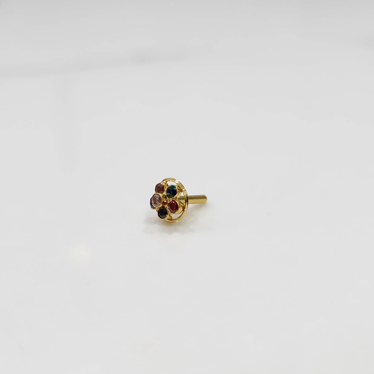 Close-up of a seven-stone multicolor gemstone nose pin in gold setting