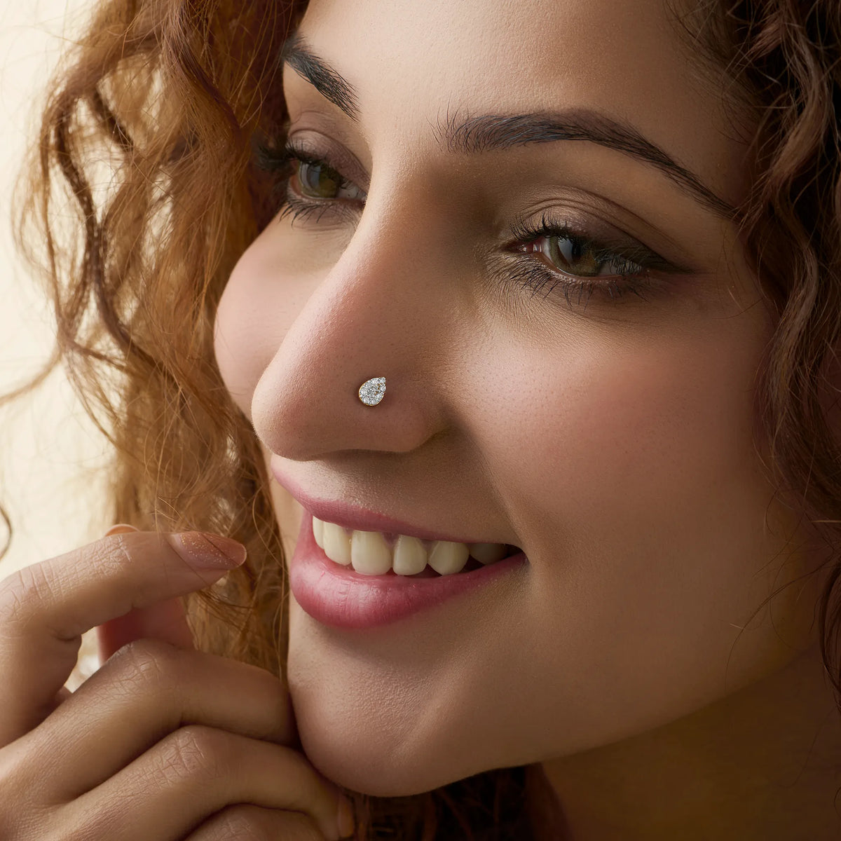 Woman wearing elegant teardrop gold nose pins with diamond shine