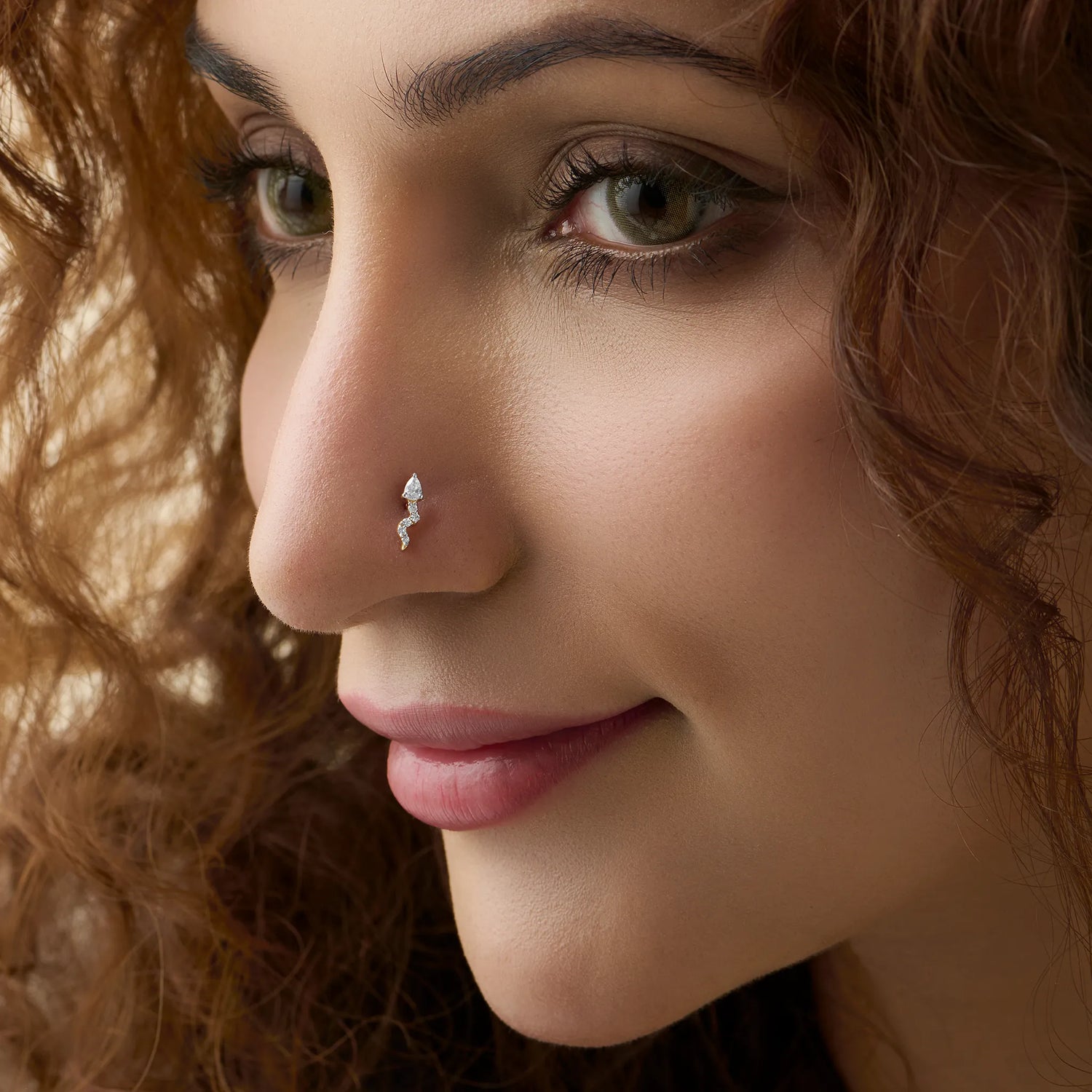 Diamond second stud price gold nose pin with pear shaped diamond and curved design on soft background