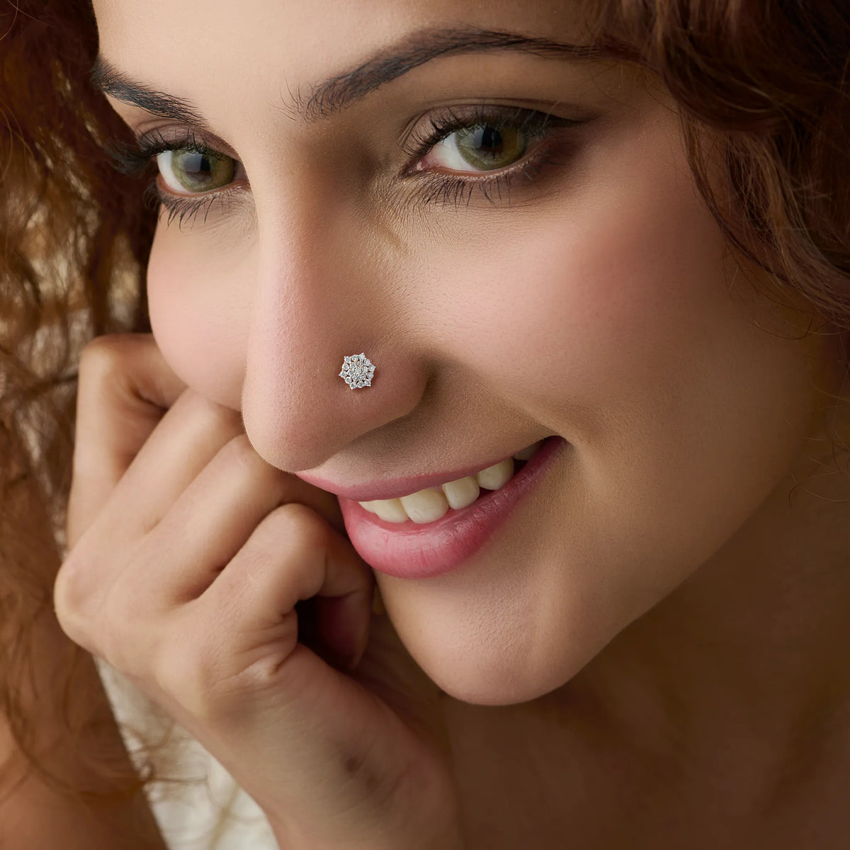Close-up of woman wearing a silver snowflake-shaped nose ring, hand near chin