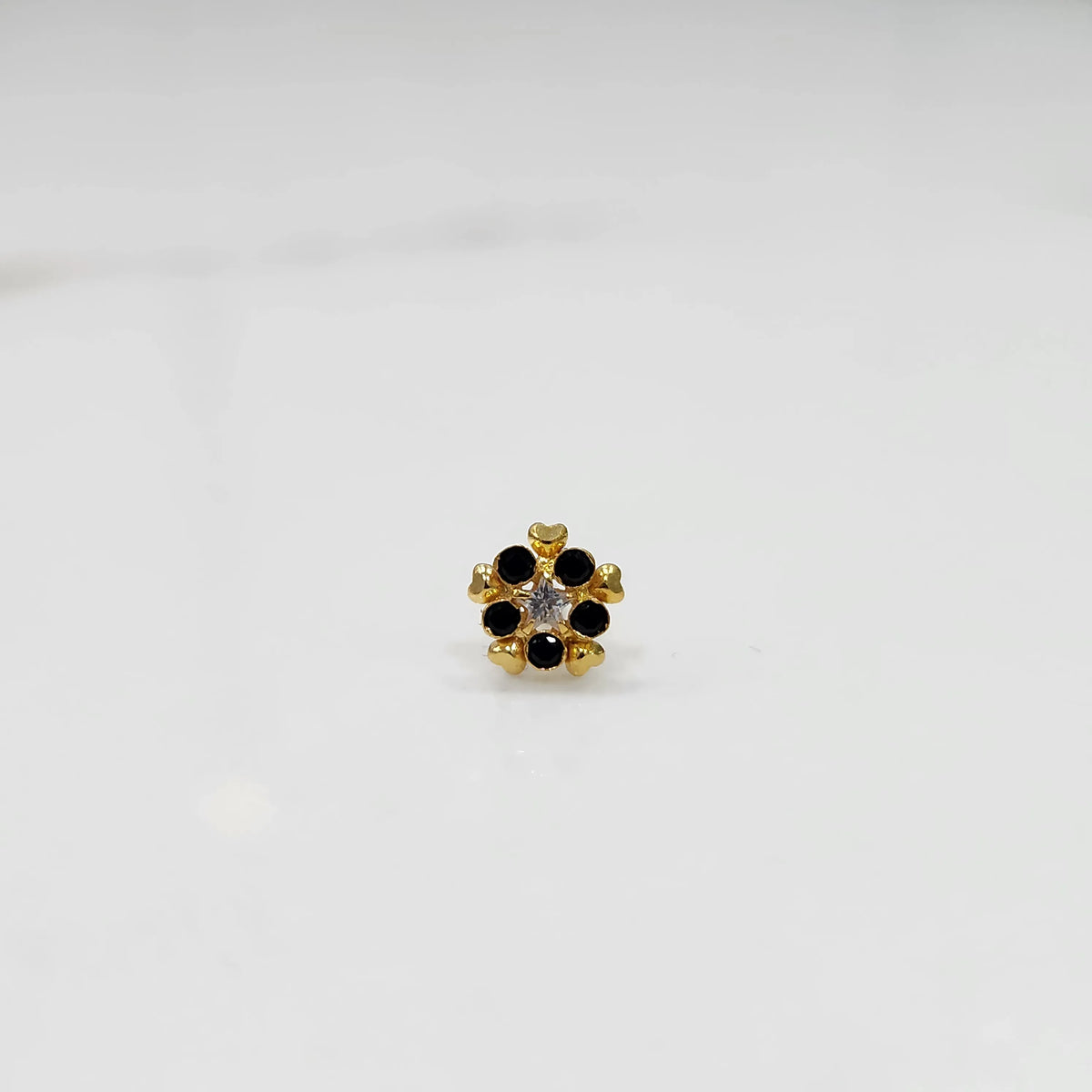 Traditional gold nose pin featuring a radiating black gemstone flower
