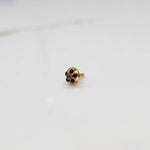 Close-up of a six-stone blue gemstone nose pin in round gold halo setting