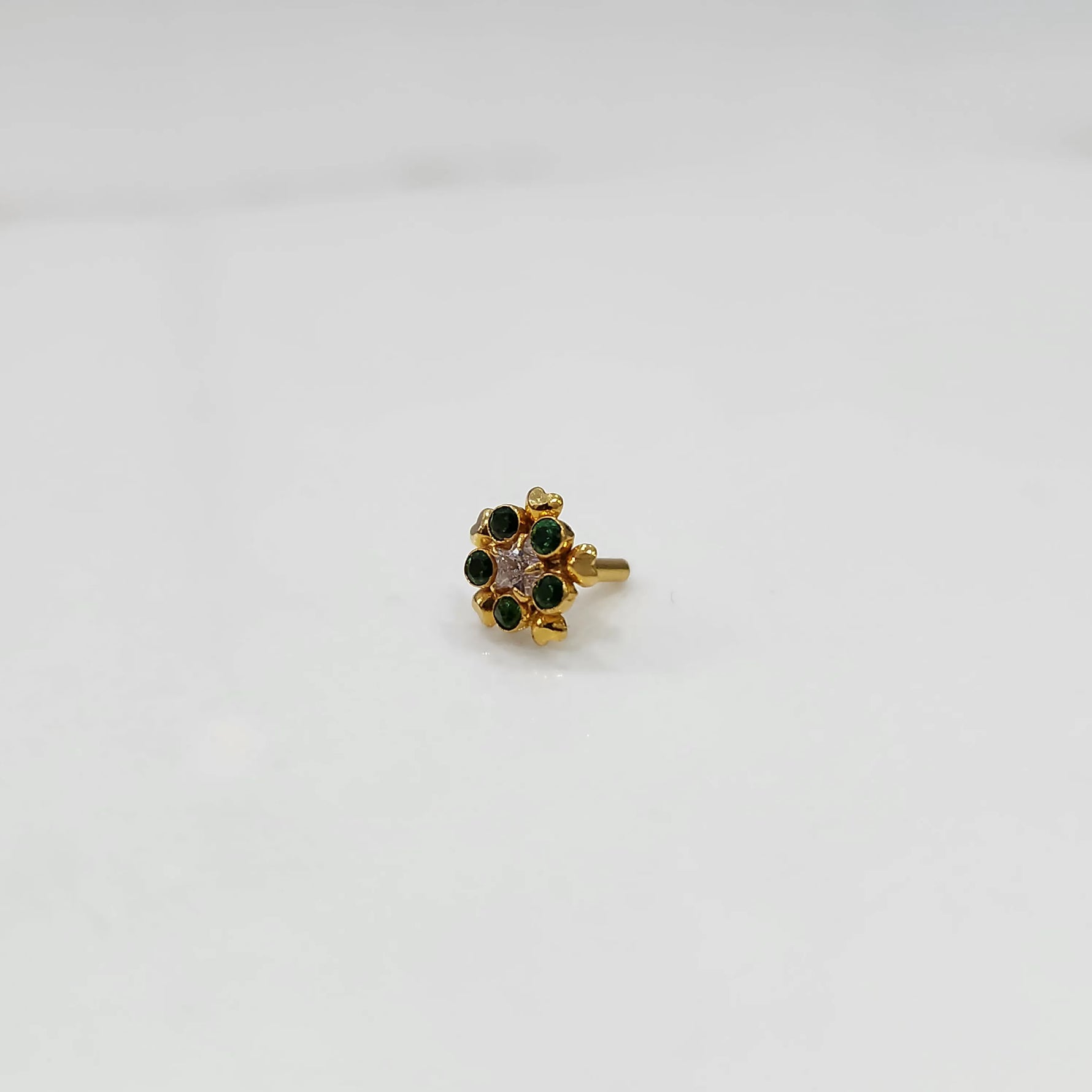 Close-up of a full-bloom green stone nose pin with gold heart accents
