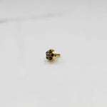 Close-up of a six-stone green gemstone nose pin in round gold halo setting
