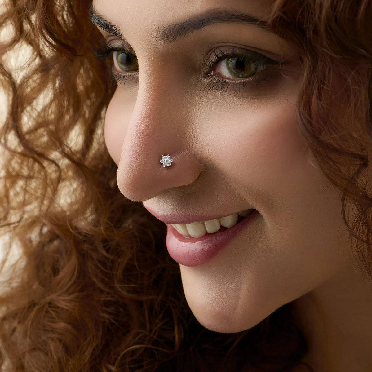 Snowflake cluster nose stud worn by a smiling woman, close-up beauty shot
