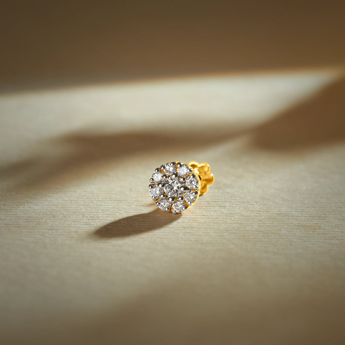 Trending nose pin gold with round floral cluster design featuring multiple sparkling stones set in a polished gold base on a soft neutral background