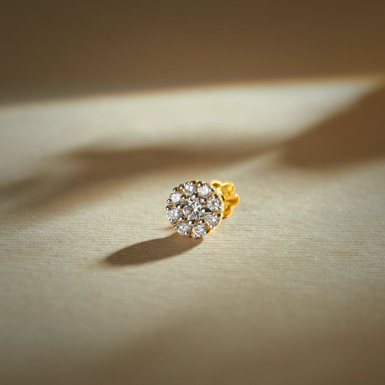 Trending nose pin gold with round floral cluster design featuring multiple sparkling stones set in a polished gold base on a soft neutral background