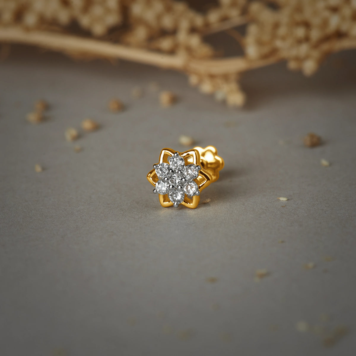 Nose pin gold with floral star design featuring sparkling stones set in a polished gold base on a soft neutral background