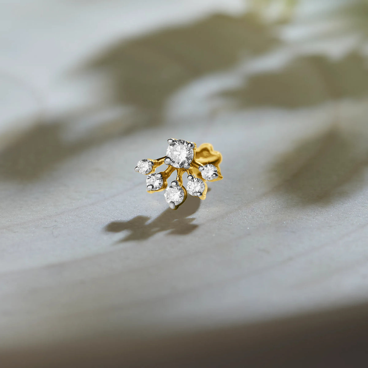 Lab grown gold nose pin with floral diamond cluster design on soft neutral background
