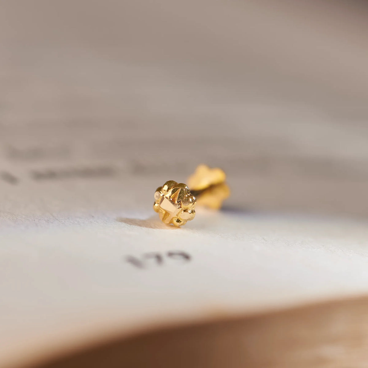 Solid gold sun or flower-shaped stud earring, macro close-up shot