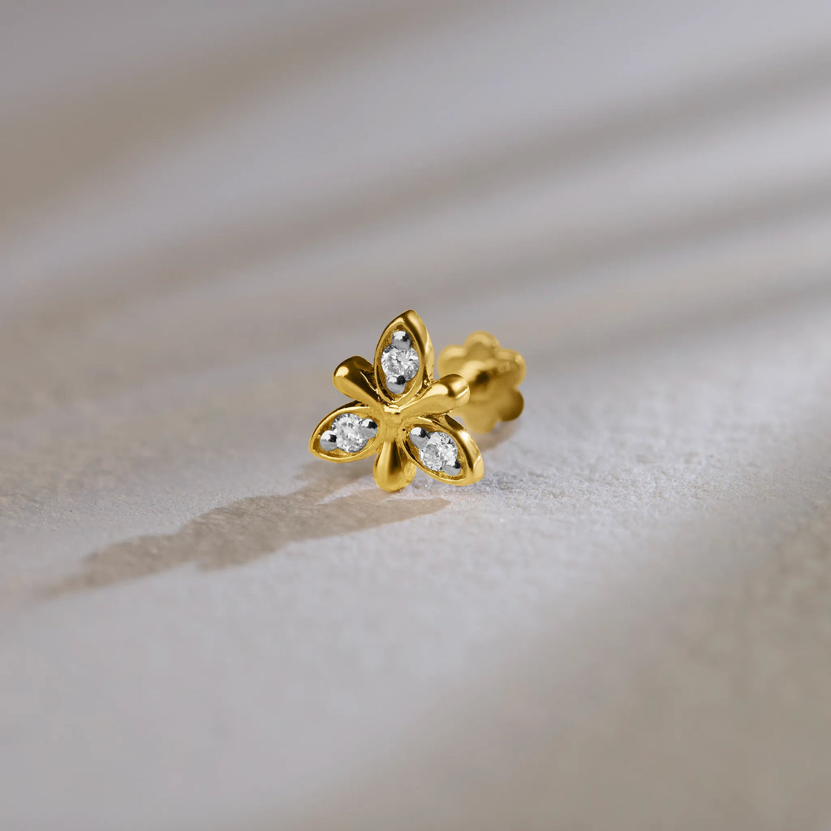 Flower-shaped stud earring with sculpted gold petals and small diamond accents