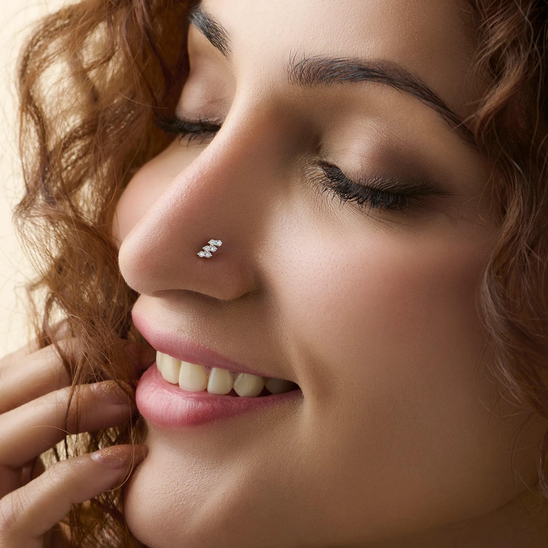 Smiling woman wearing stylish gold nose pin side profile portrait