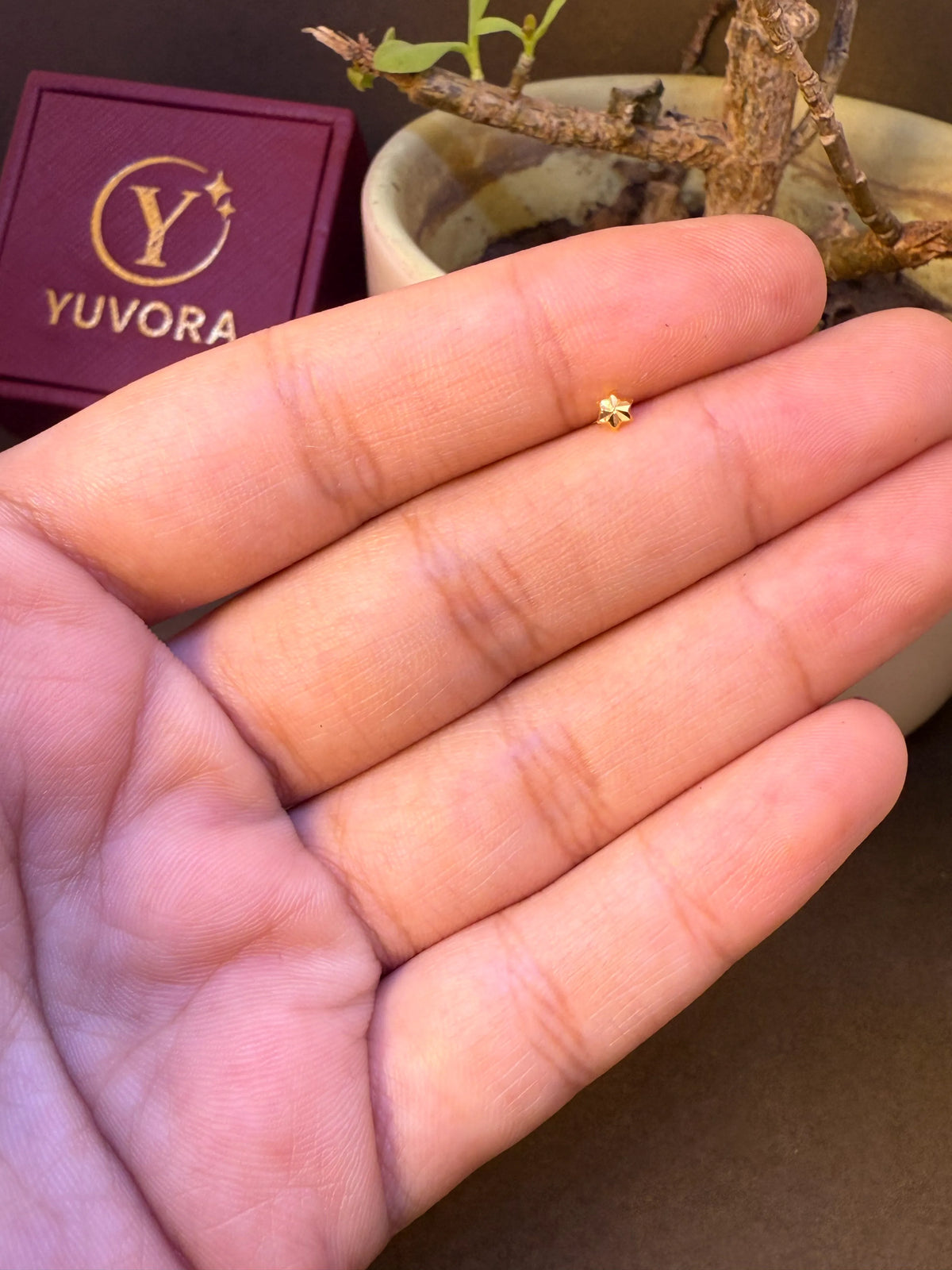 Close-up of four-leaf clover-shaped gold nose pin with heart petals