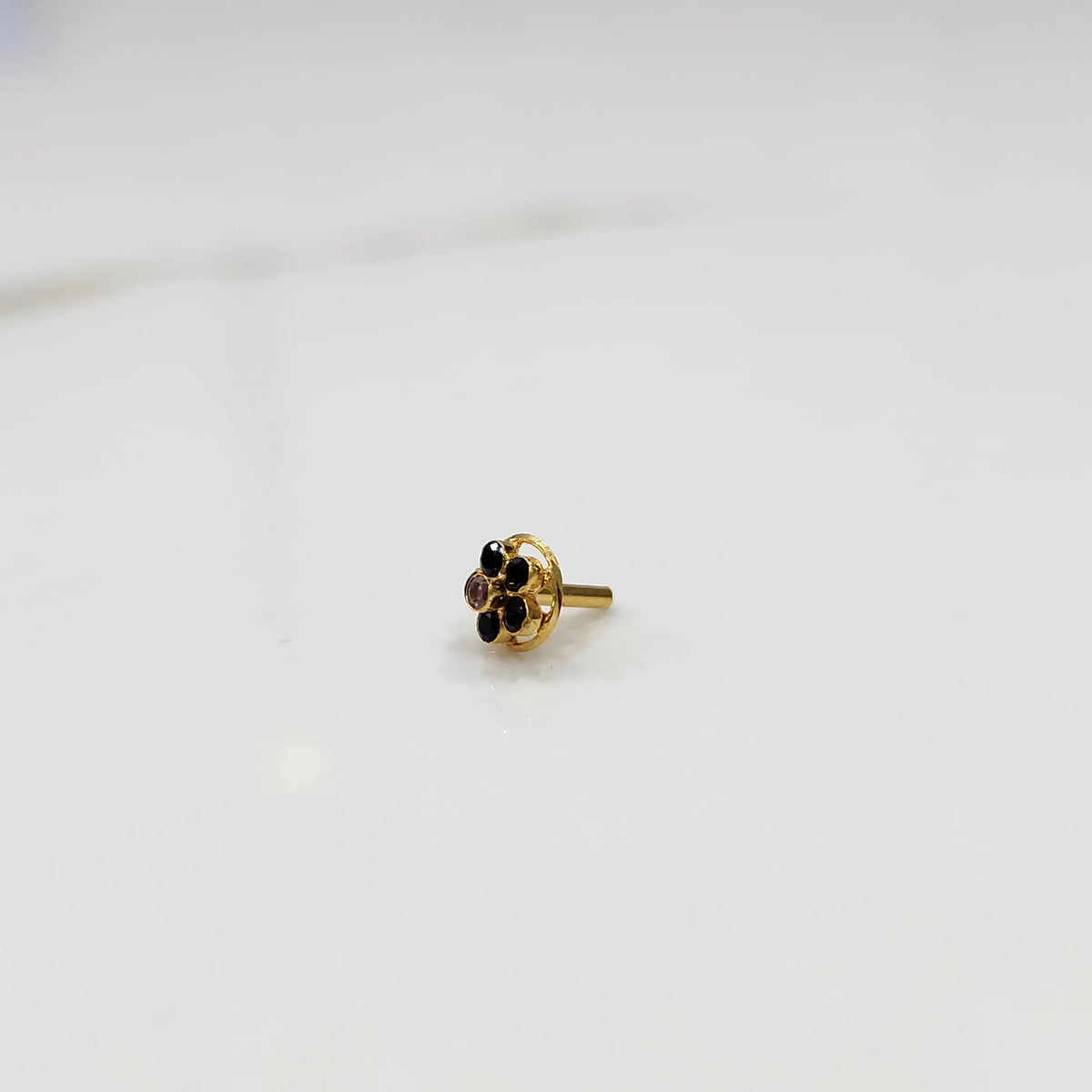 Traditional gold nose pin featuring a round black gemstone flower design