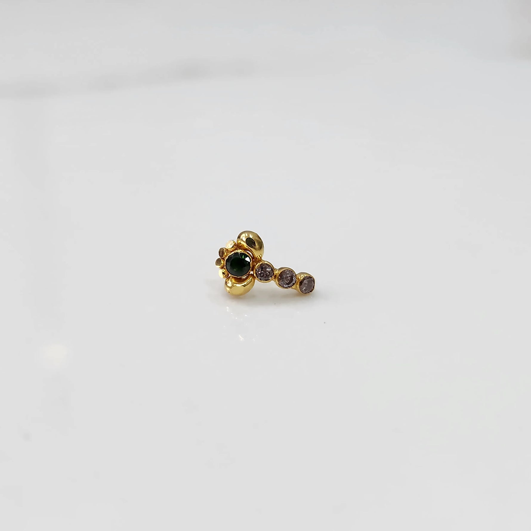 Front view of gold nose pin with green floral head and stone trail