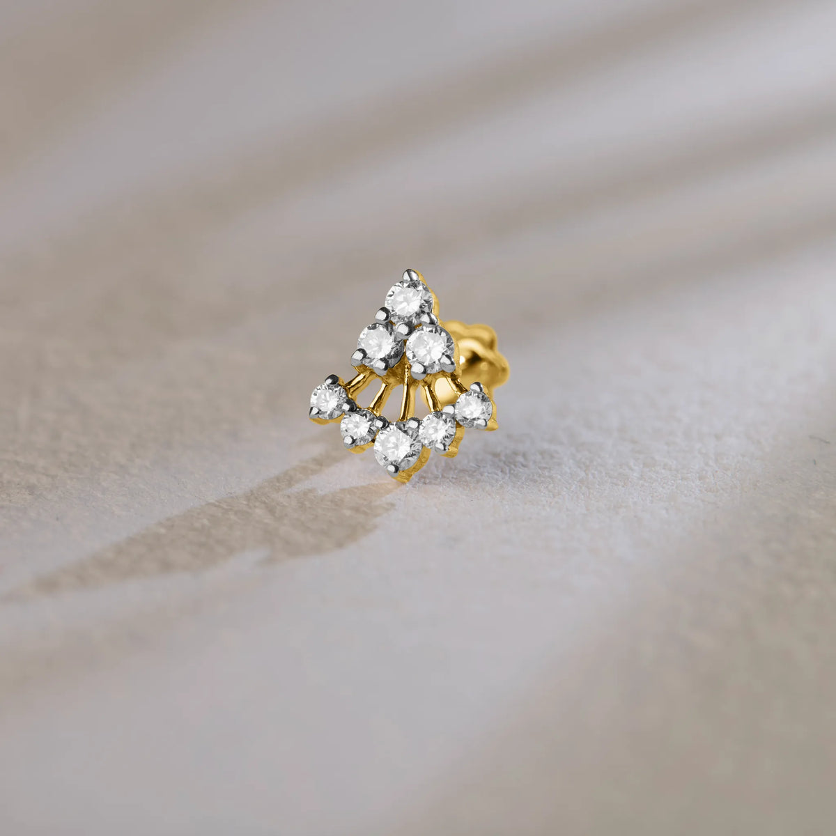 Triangle cluster lab grown gold nose pin with sparkling diamonds on soft background
