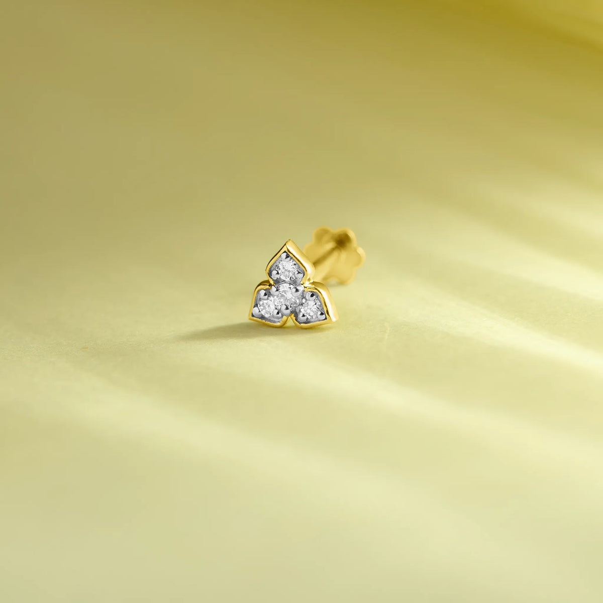 Lab grown diamond nose pin with three stone floral design in gold on soft yellow background