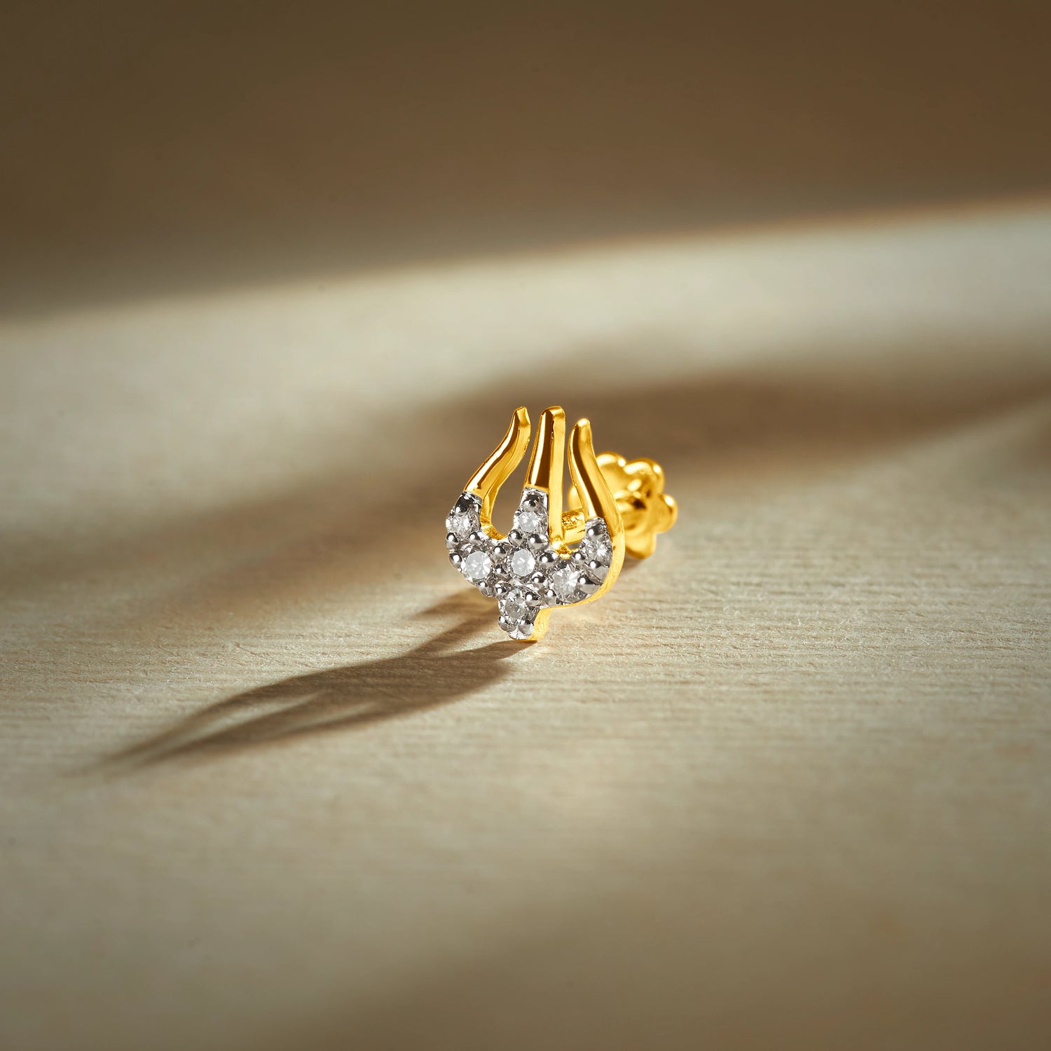 Trending nose pin gold with abstract curved design featuring sparkling stones set in a polished gold base on a soft elegant background