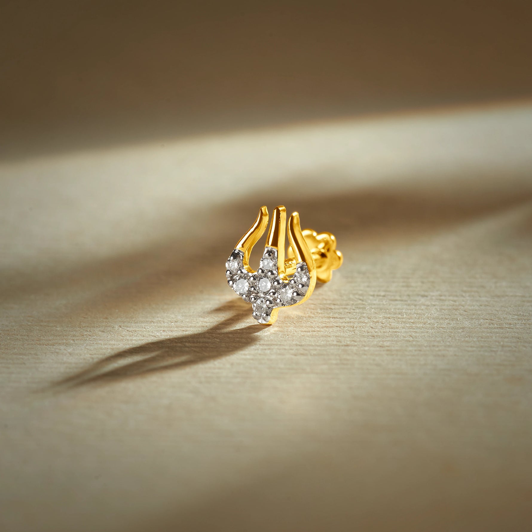 Trending nose pin gold with abstract curved design featuring sparkling stones set in a polished gold base on a soft elegant background