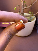 Leaf-shaped gold and silver two-tone nose pin, held between fingertips