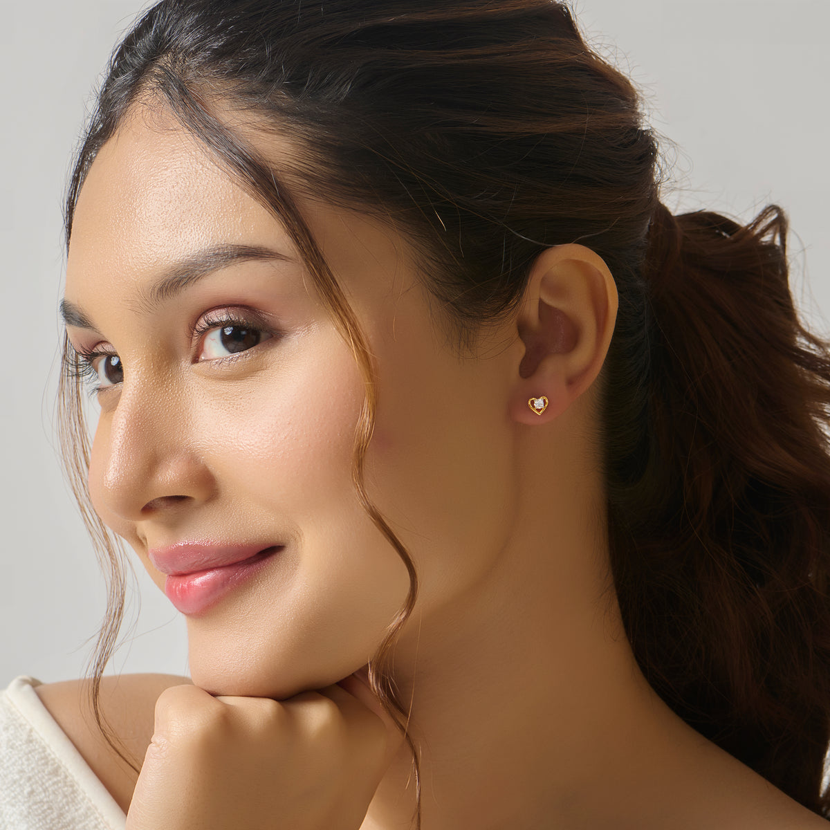 Close-up of woman wearing gold heart stud earring