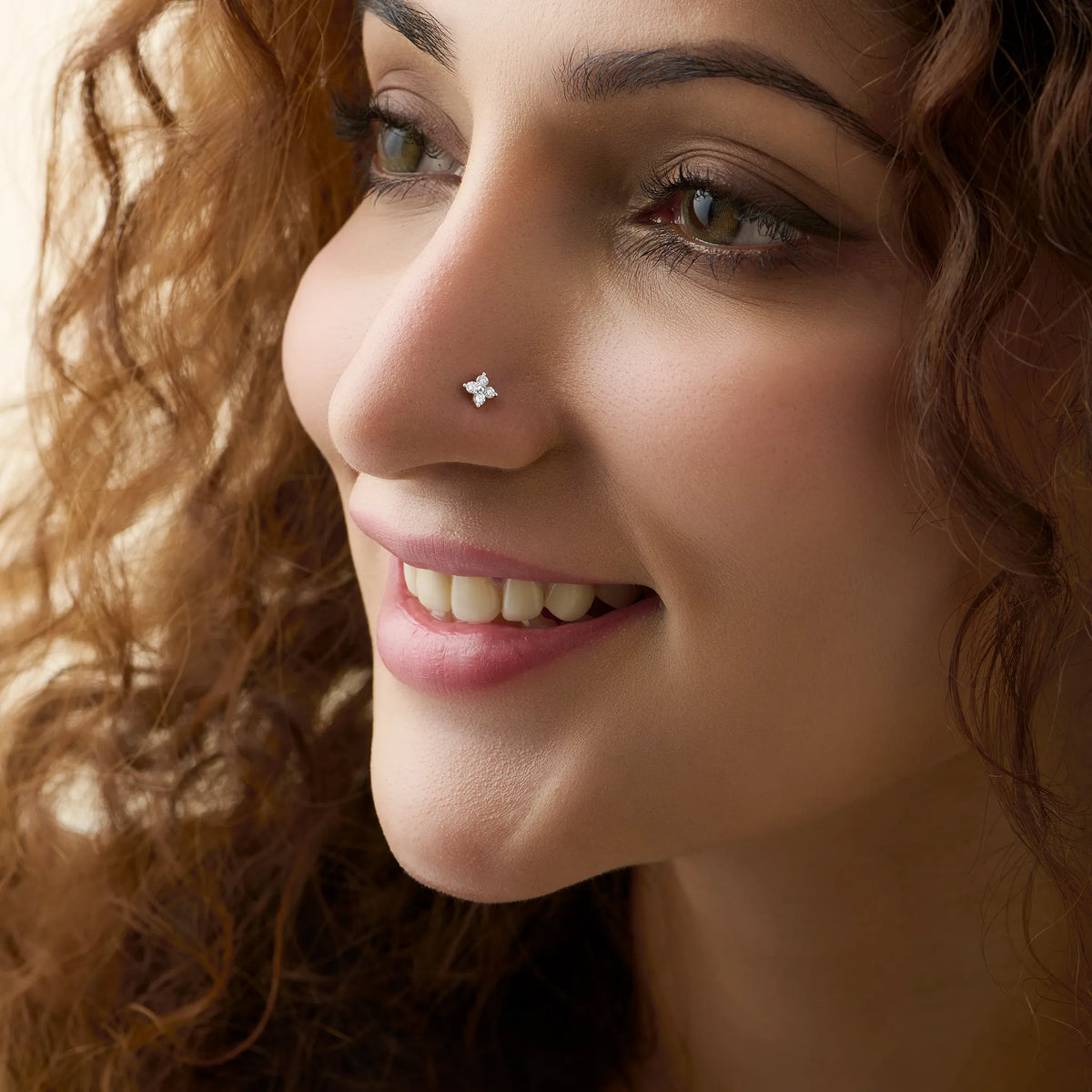 Square diamond nose stud worn by a smiling woman, close-up beauty shot