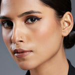 Close-up of woman wearing gold flower-shaped nose stud with winged eyeliner