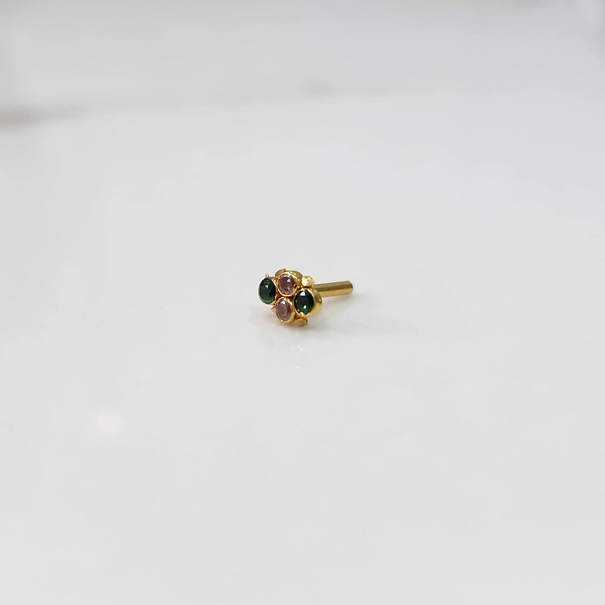 Women's gold nose pin design with gemstone floral setting on white background