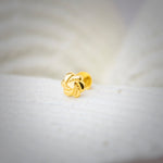Front view of knot-shaped 18K nose pin gold placed on a soft white surface highlighting its detailed textured design
